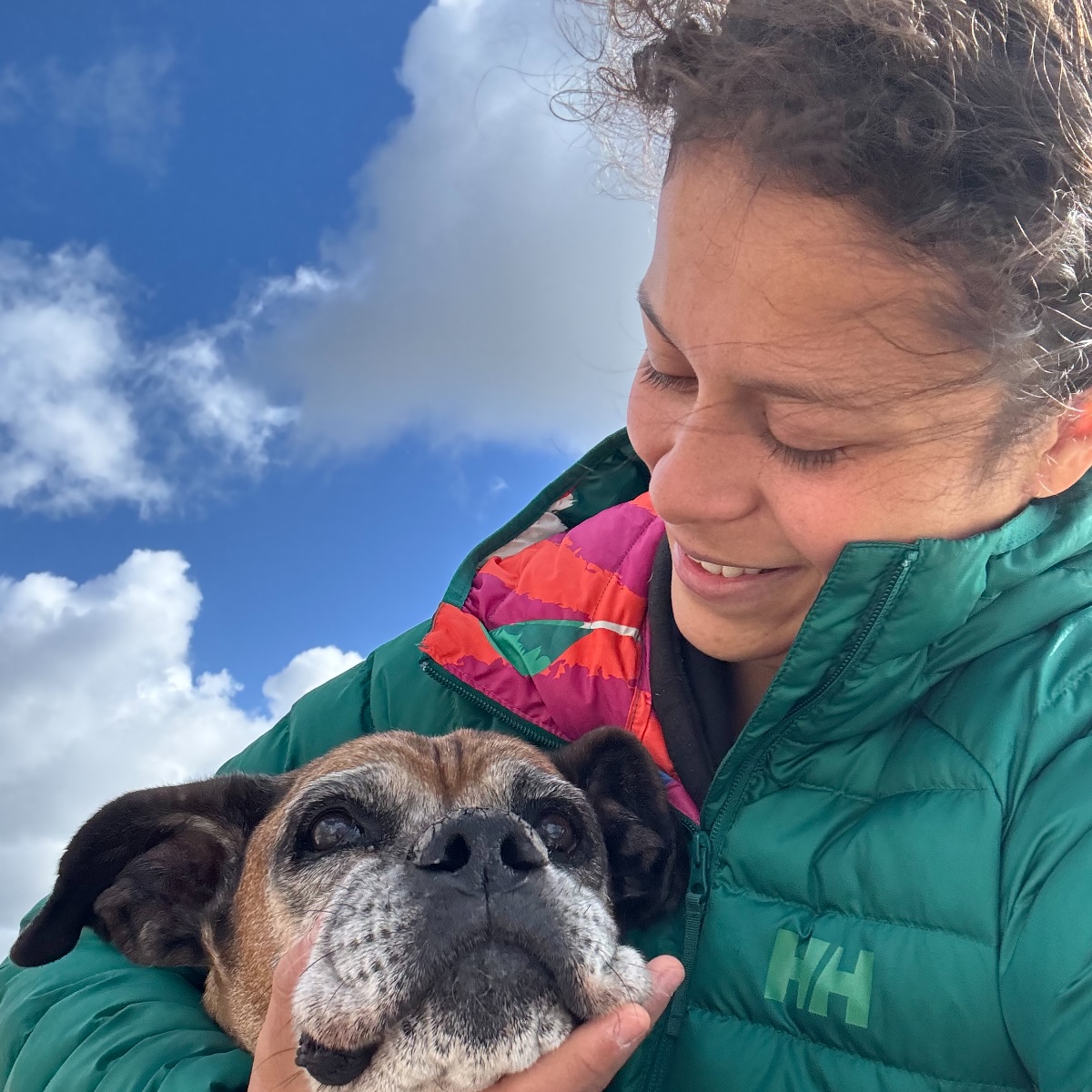 Maria cuddling her boxer dog on the beach